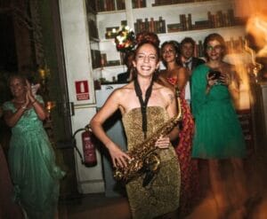 Nasha Sak, saxofonista sonriendo con muchas chicas alredeor mientras toca su saxo en una boda en Madrid