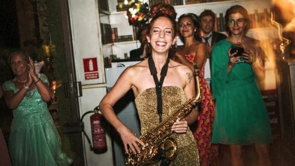 Nasha Sak, saxofonista sonriendo con muchas chicas alredeor mientras toca su saxo en una boda en Madrid